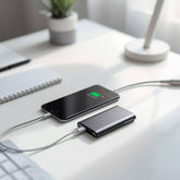 Phone charging with a power bank on a desk with a plant and lamp in the background